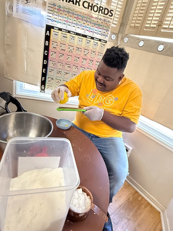 Adult with disabilities using grater to zest lemon into bowl while learning food preparation skills at Ivey Ranch adult day program