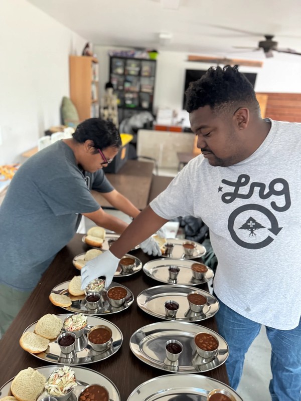 Woman in adult day program spreading dessert mixture onto foil-covered baking sheet while developing food preparation and presentation skills