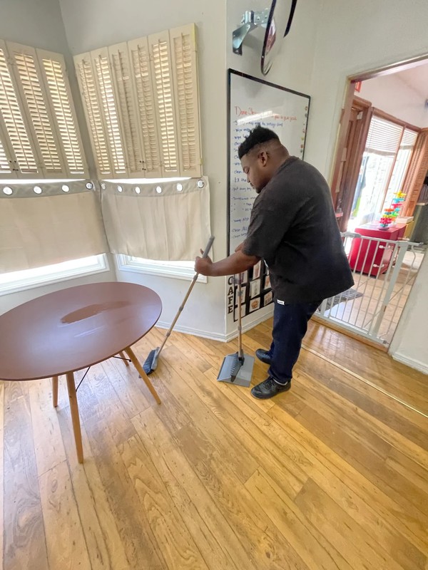 Adult with disabilities learning household cleaning and floor sweeping techniques as part of independent living skills training at Ivey Ranch