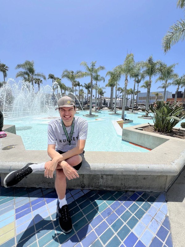 Adult day program participant enjoying community outing at public fountain area in San Diego County