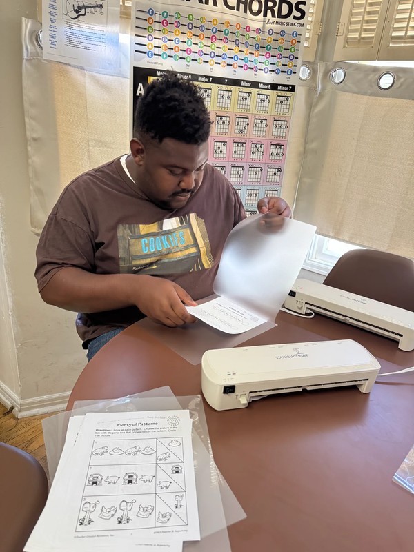 Adult day program participant learning vocational office skills by laminating documents at Ivey Ranch Park Association program facility