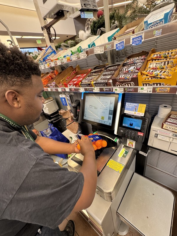 Adult with developmental disabilities learning money management and checkout skills at grocery store register