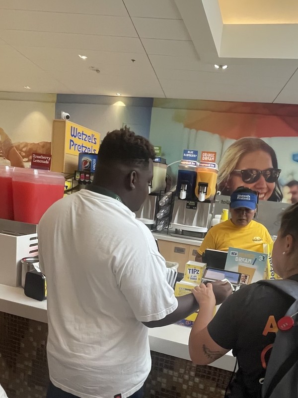 Adult with developmental disabilities practicing food ordering and payment skills at Wetzel's Pretzels food counter
