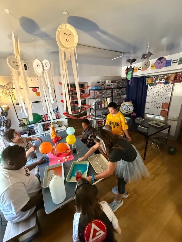 Group of adults engaged in various sensory activities in colorful art room with decorative installations overhead