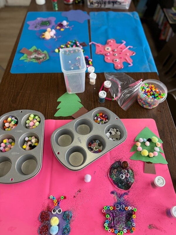 Arts and crafts table setup with muffin tins filled with colorful beads, glitter jars, and completed sea creature crafts at Ivey Ranch School-Age Program