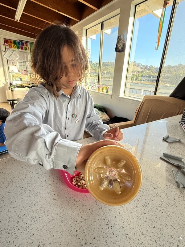 Student carefully mixing cereal and ingredients in yellow bowl during hands-on baking lesson at school age program kitchen