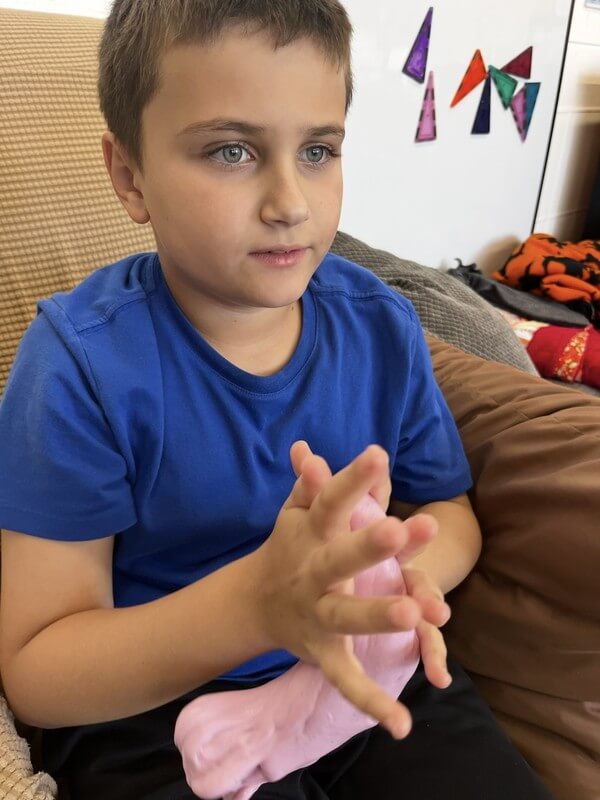 Young boy engaged in hands-on slime-making activity at school-age program, developing fine motor skills through fun sensory play and creative crafts.