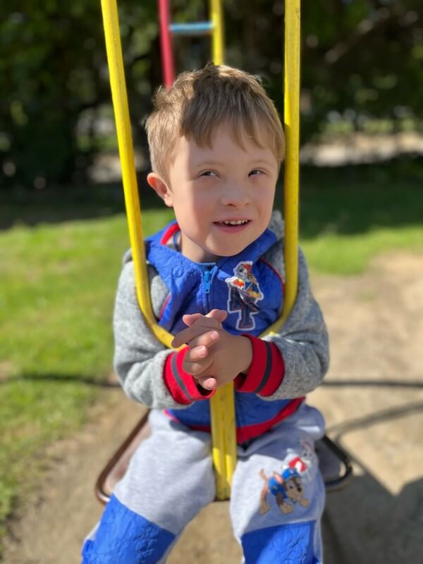 Happy child playing on outdoor swing set at after-school program, enjoying supervised playground time in a safe and inclusive environment.