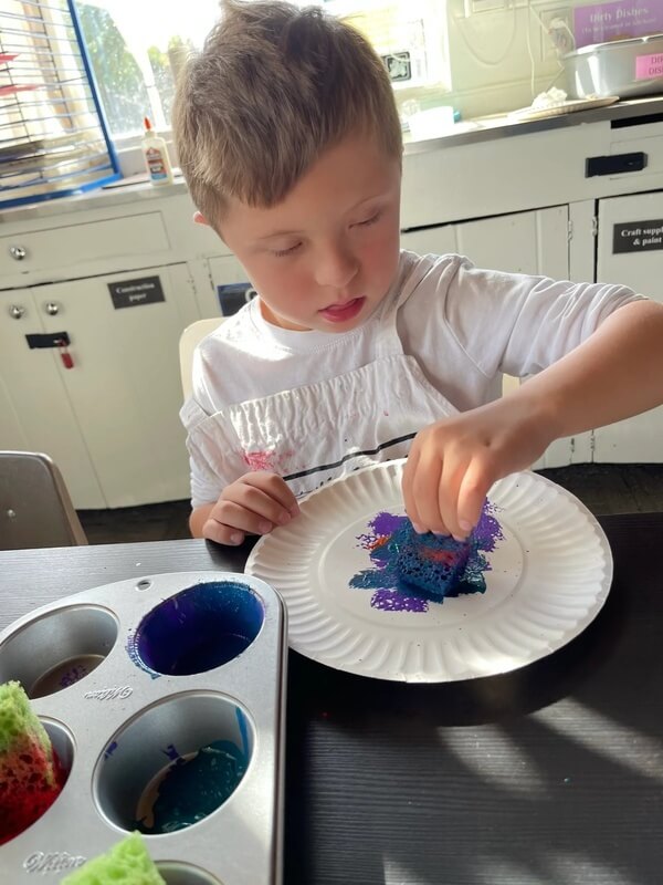 School-age child concentrating on sponge painting on paper plate