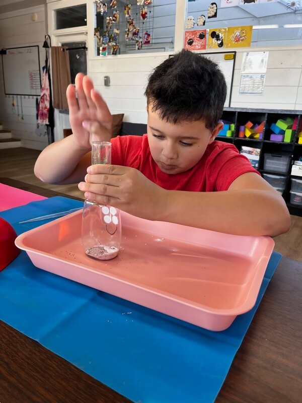 Child filling up a jar with sensory ingredients