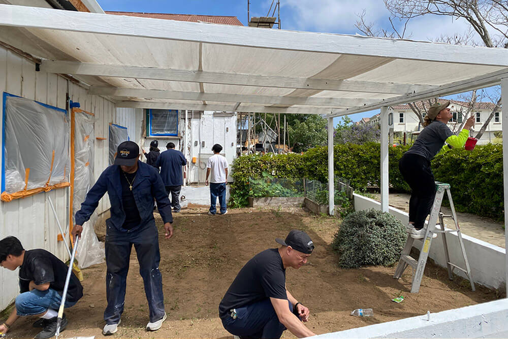 A group of volunteers painting and making ground repairs to ranch buildings during a service project at Ivey Ranch Park Association in Oceanside, California