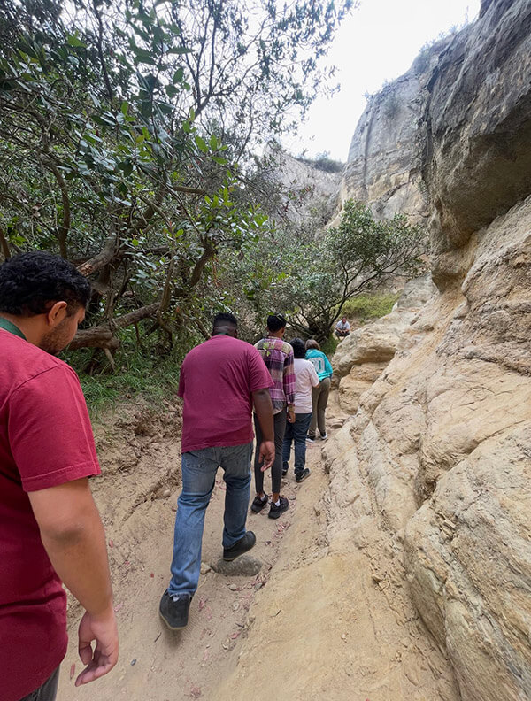 Ivey Ranch Adult Day Program participants hiking through a narrow slot canyon during a community outing