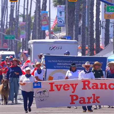 Ivey Ranch Park Association volunteers and staff marching with a banner in the Oceanside Independence Parade