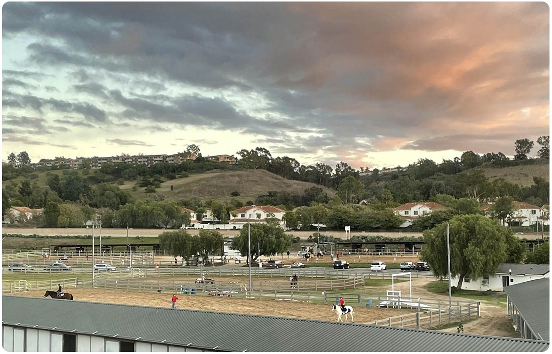 Riders and volunteers in the arena at Ivey Ranch during sunset in Oceanside, CA