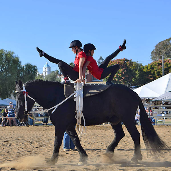 Two riders performing a vaulting demonstration on horseback during the Western Hoedown